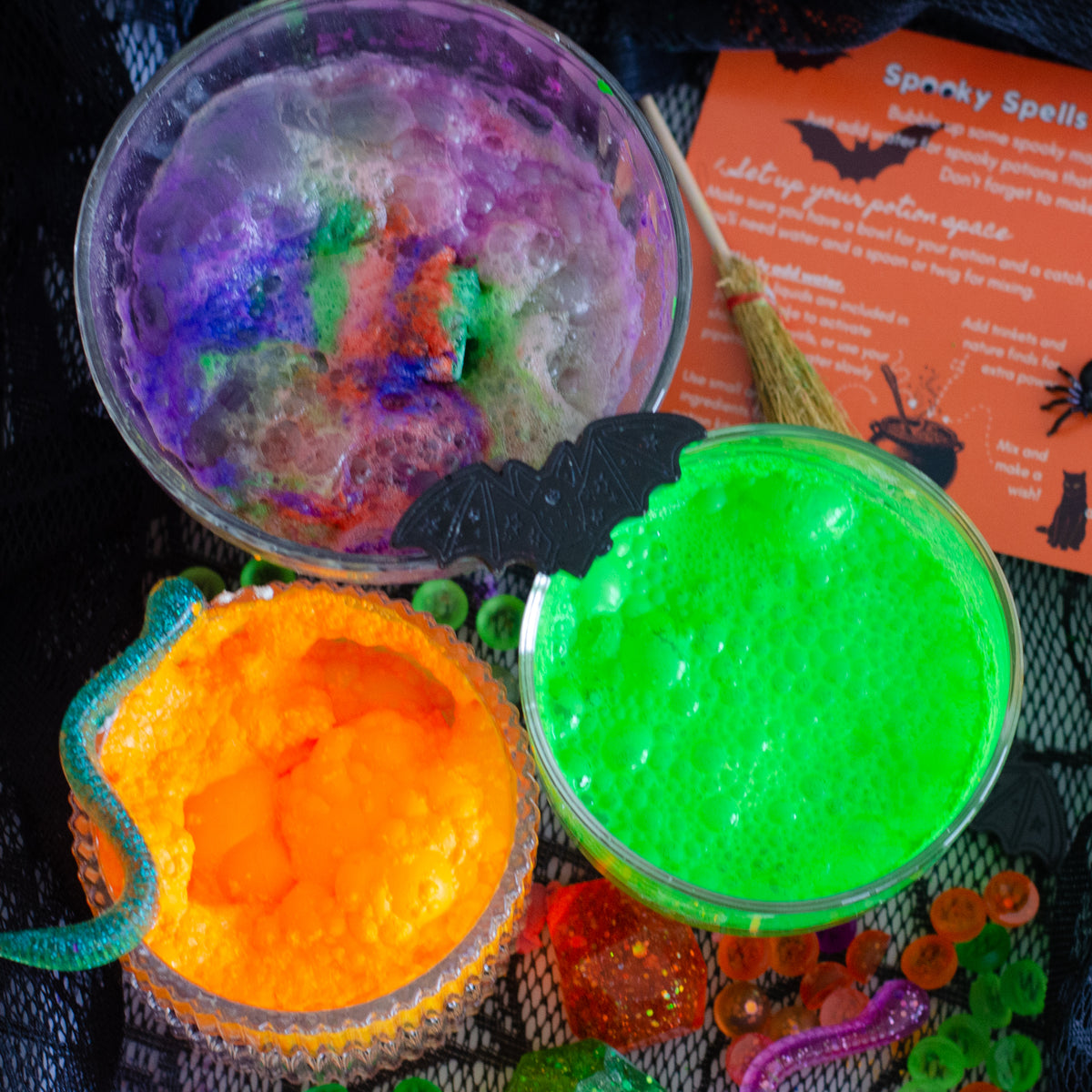 Three colorful spooky-themed potions showing fizz and foamy in orange, green and purple for a Halloween Potion making kit for kids, by Cherry Bumbles Potions.