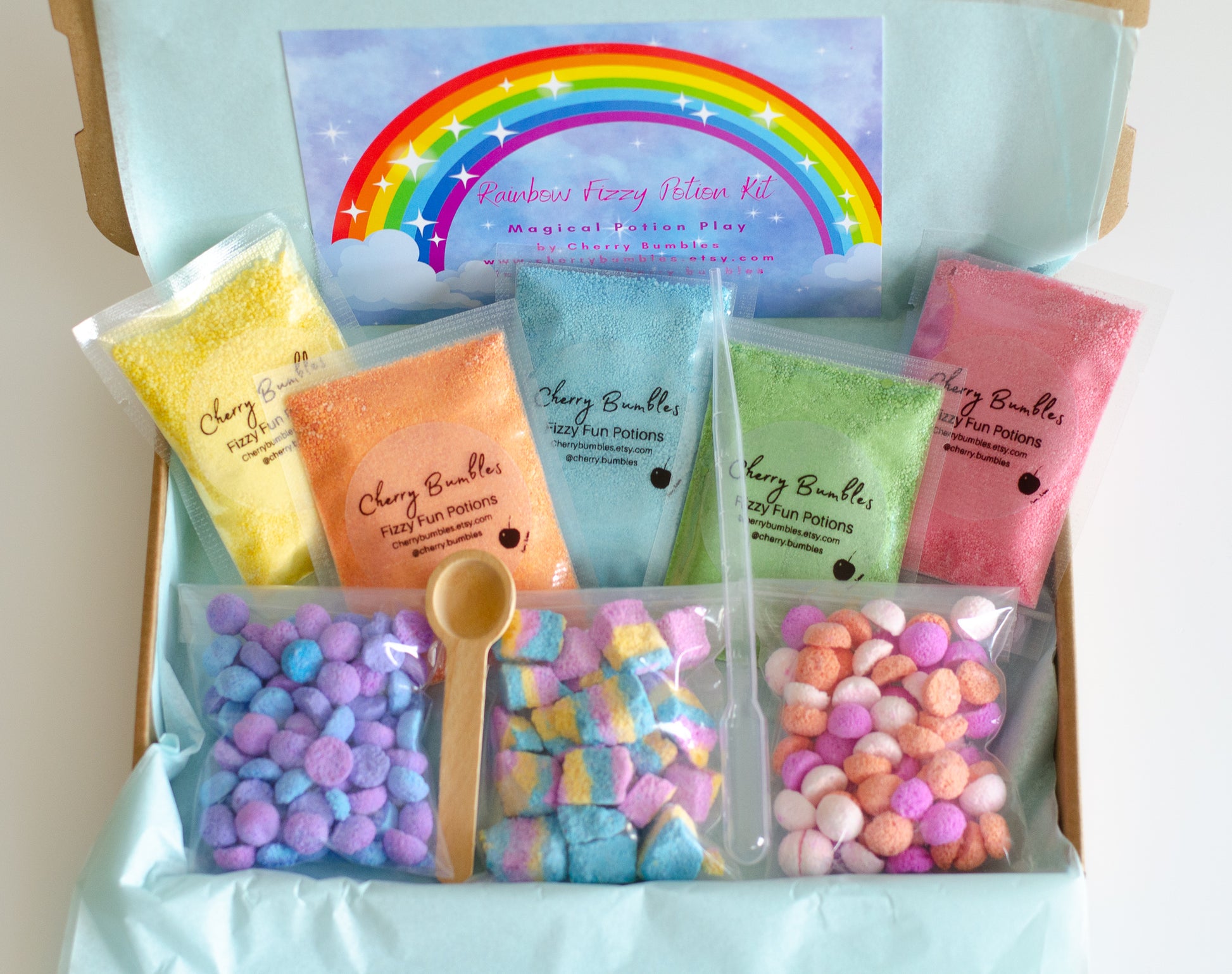 rainbow potion kit shown in box, including fizzy potion powders, foaming rocks, and potion utensils. 